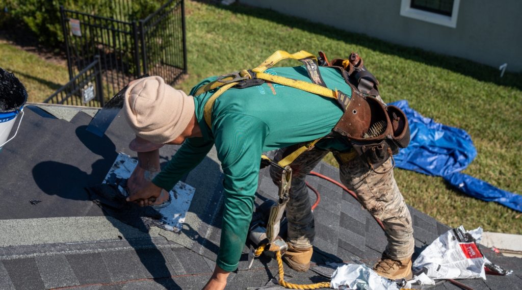 A man working on a roof with a tool, representing Roofers Tampa FL in action.